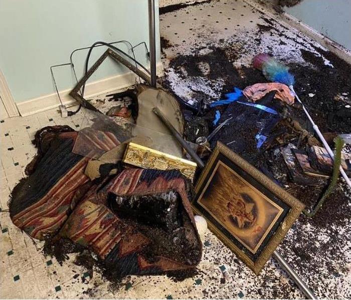 various home items including portraits and furniture charred on the floor in a laundry room. 