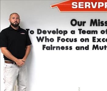 Tech standing in front of our mission statement