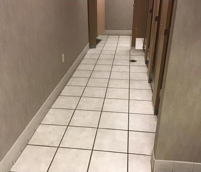 men's restroom with beige tile floors and brown stall doors to the right. 