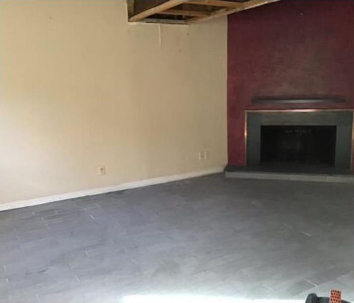 living room with fireplace and burgundy red painted wall above it and cream colored walls on the side with torn up flooring.