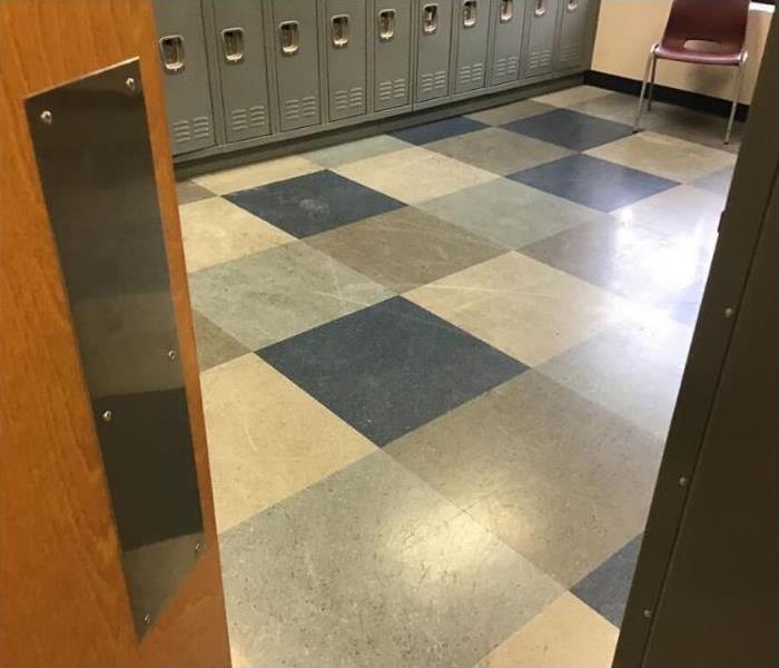 locker room floors with blue, yellow, and other varying color tile squares. Lockers to the left. 